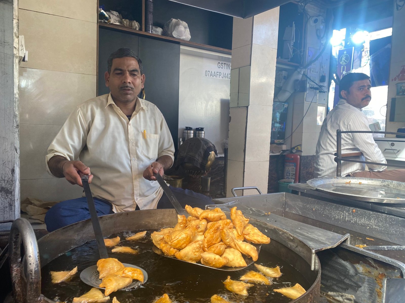 A street food vendor in Delhi preparing traditional Indian snacks at a busy market stall