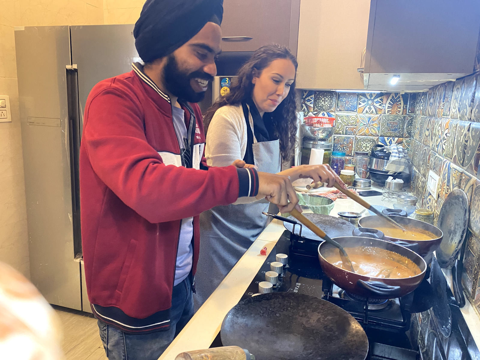 Travelers cooking with a local family in a Delhi home kitchen