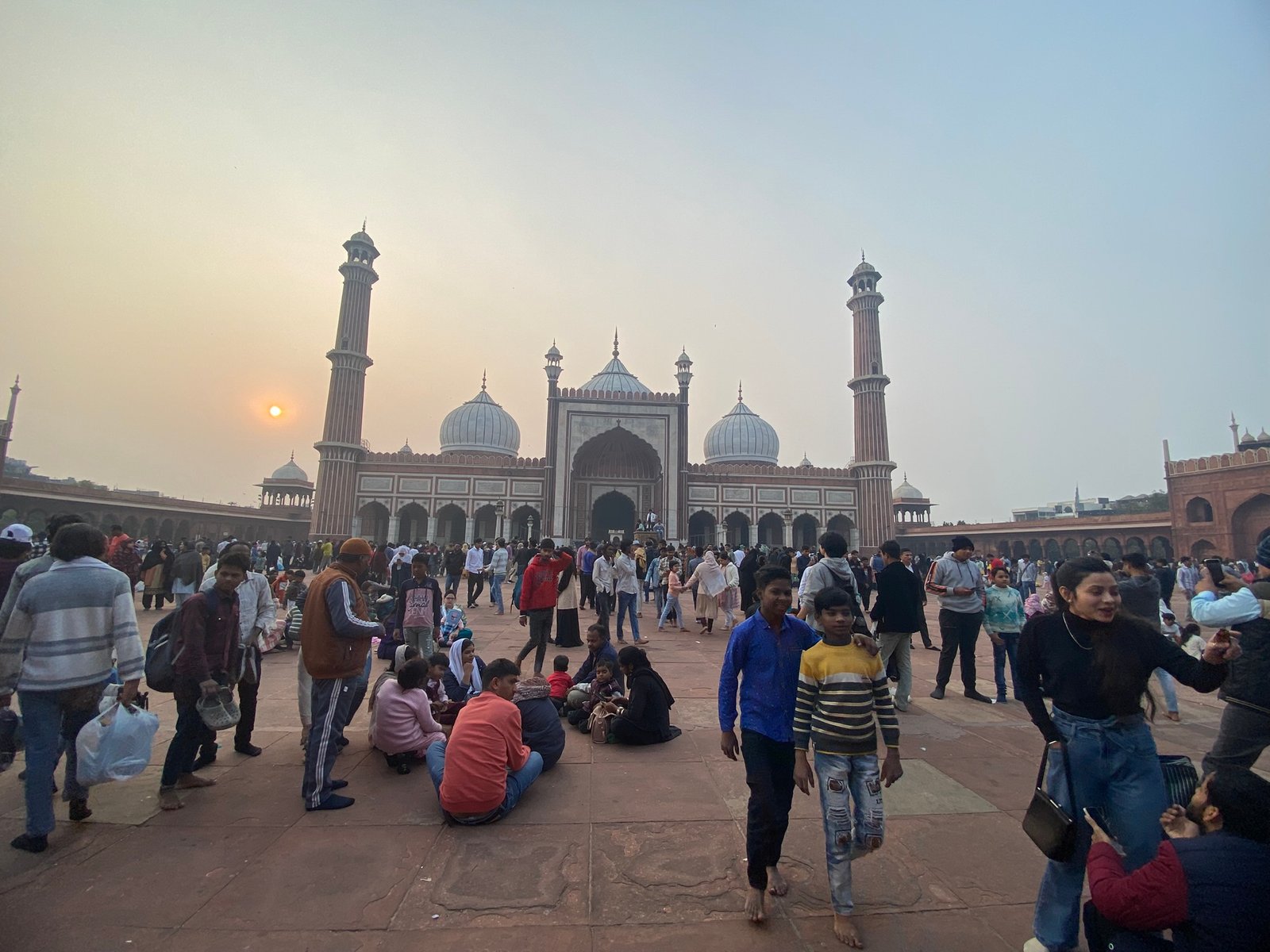 Visitor taking photographs of Jama Masjid minarets against blue sky