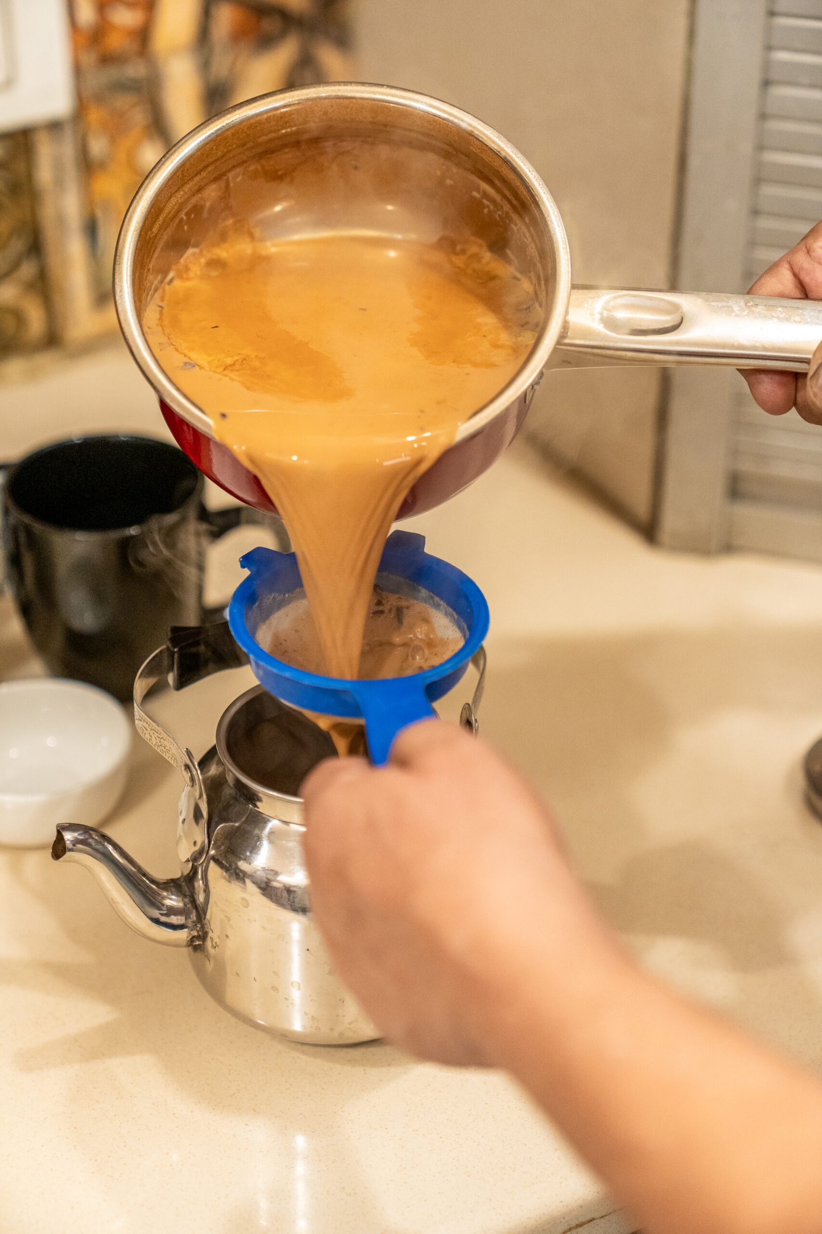 Traditional chai brewing technique showing milk being added to tea