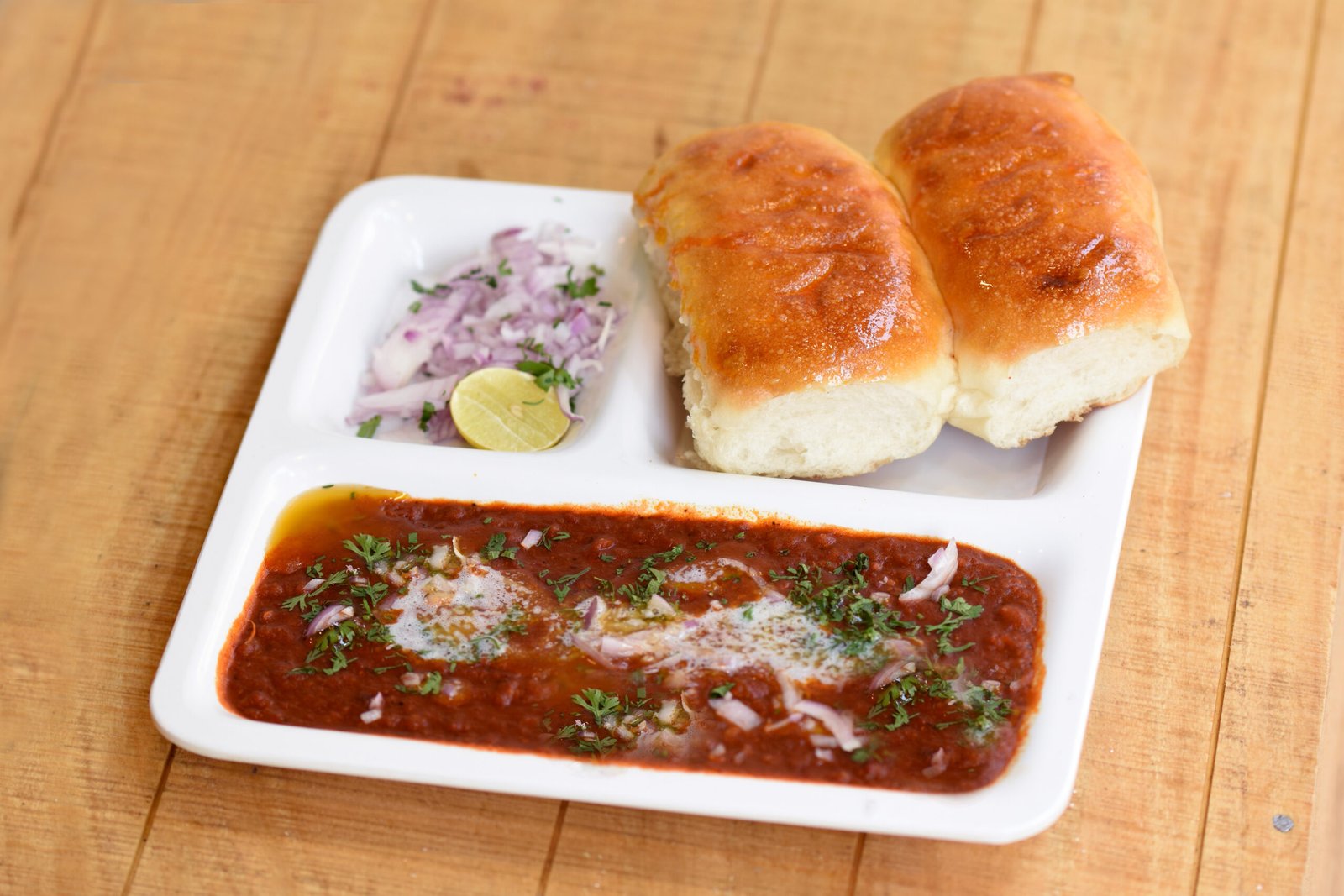 Pav bhaji served with buttered pav bread and chopped onions