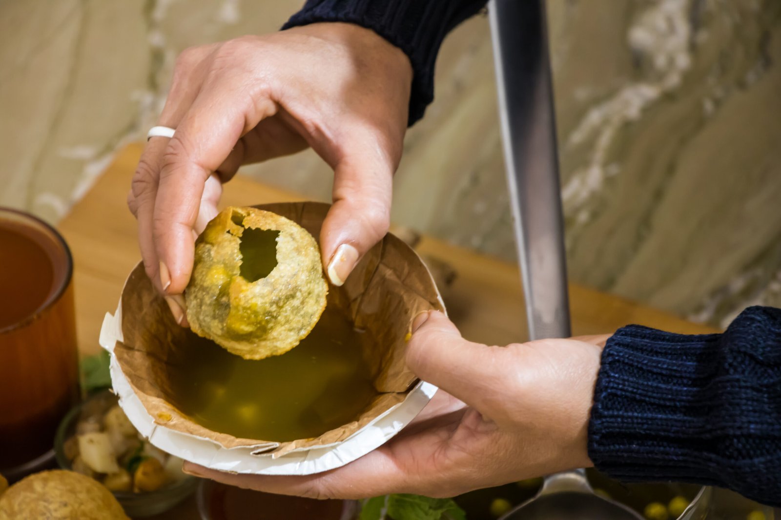 Golgappa served with tamarind water and spiced potato filling on a plate