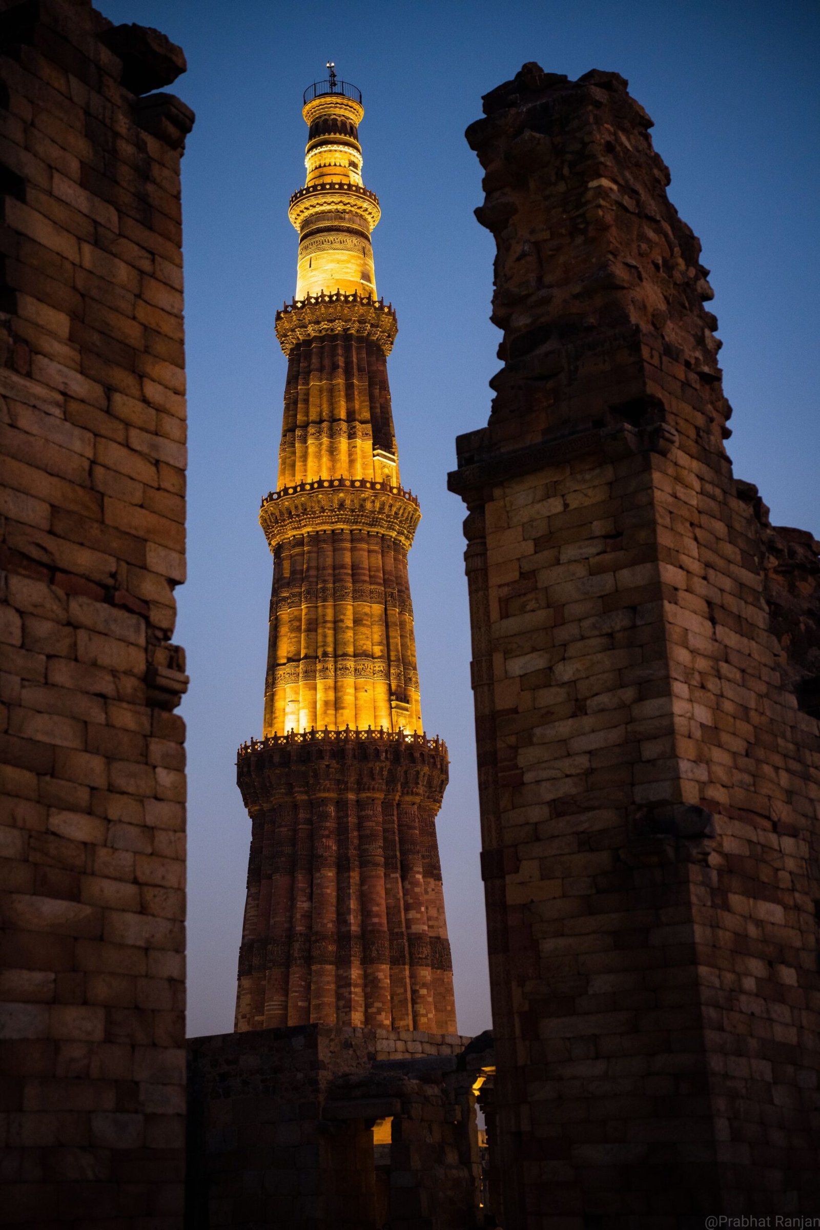 Qutub Minar illuminated at night against dark sky in Delhi