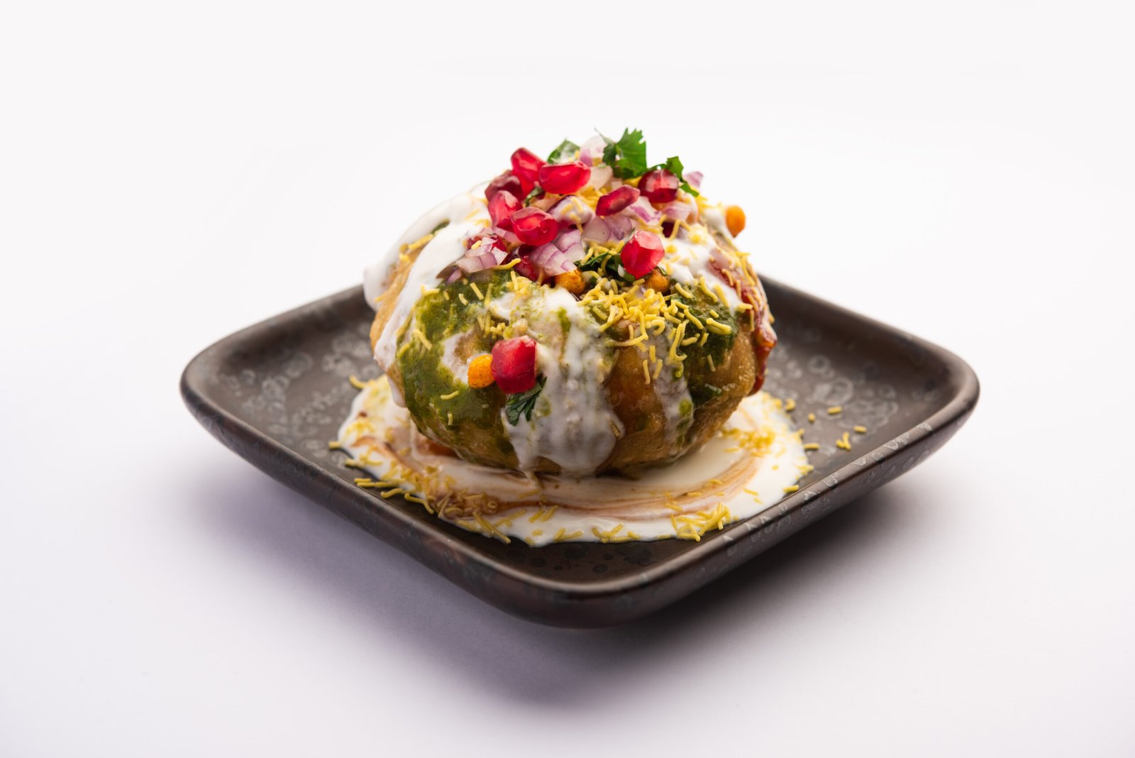 Raj kachori stuffed with lentils yogurt and chutneys on a plate