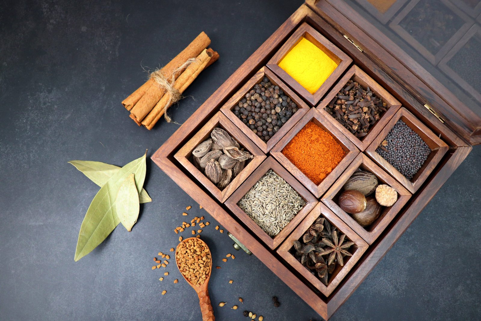 Variety of Indian spices and herbs arranged in a traditional wooden spice box
