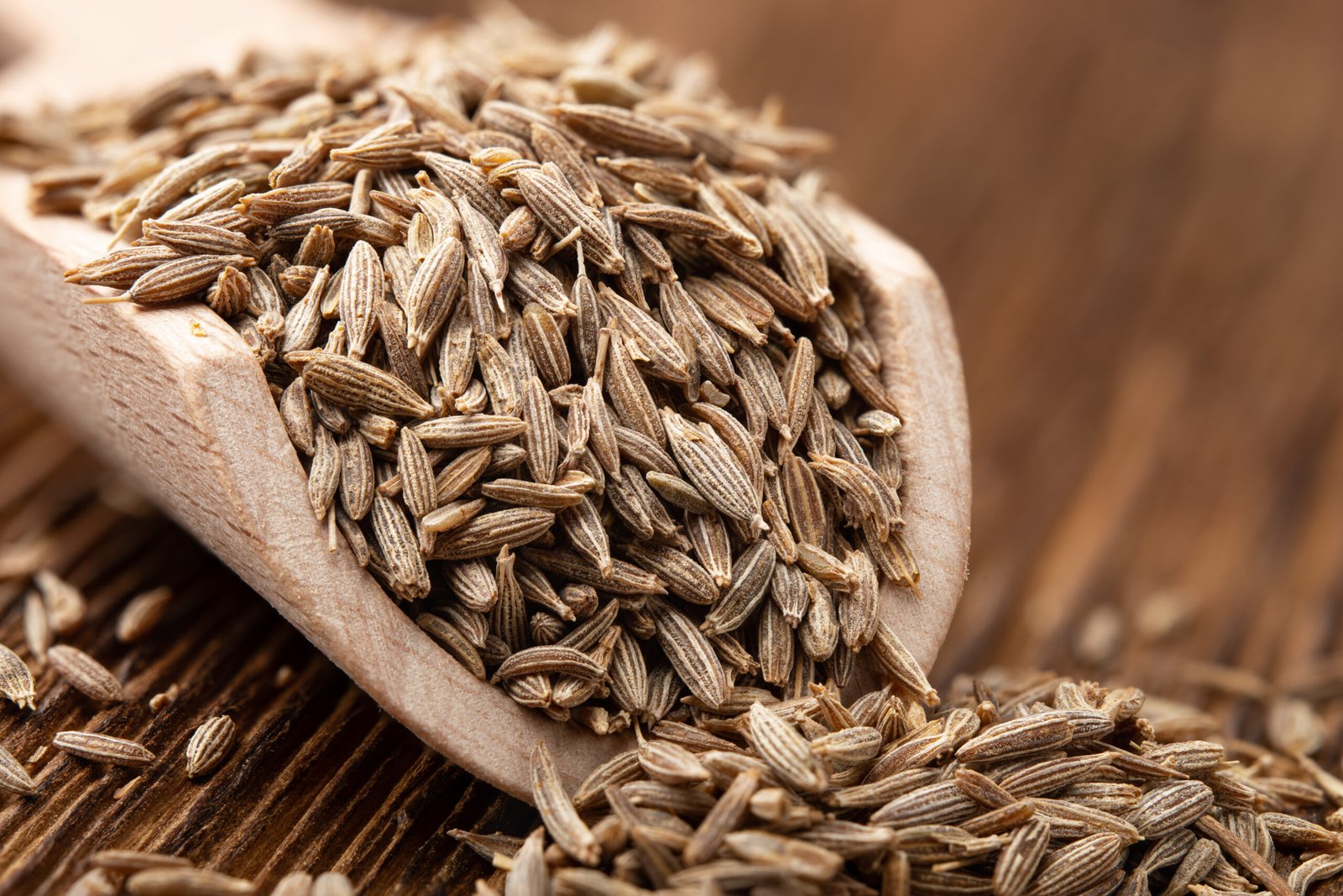 Whole cumin seeds, jeera, in a wooden scoop
